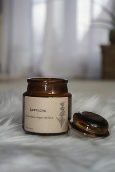 a candle sitting on top of a white blanket next to a wooden container with a lid