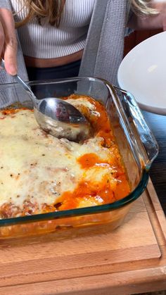 a woman scooping some food out of a casserole dish with a spoon