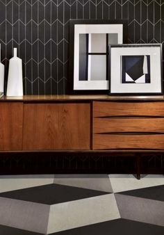 three framed pictures sit on top of a wooden cabinet in front of a black and white checkered floor