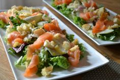 two white plates filled with salad on top of a wooden table