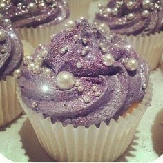 purple cupcakes with blue frosting and sprinkles sitting on top of each other