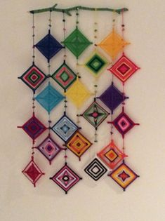 a multicolored art piece hanging on the wall with beads and string attached to it