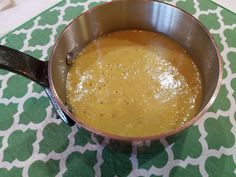 a metal pan filled with yellow liquid on top of a green and white table cloth