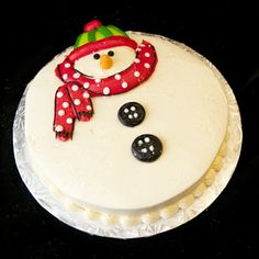 a cake decorated with a snowman and two black buttons on it's side