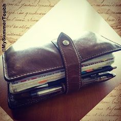 a wallet with several pens and pencils in it sitting on top of a table