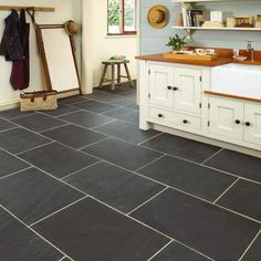 a kitchen with black slate tile flooring and white cabinetry, along with a wooden countertop