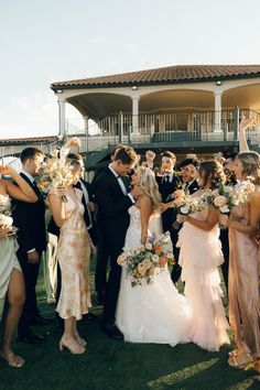 a group of people standing next to each other in front of a building with flowers