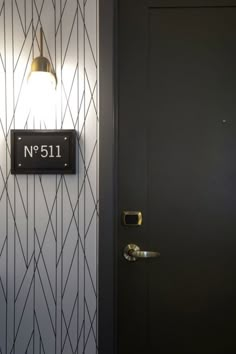 a black door with a light on it next to a wall mounted sign that reads no 511