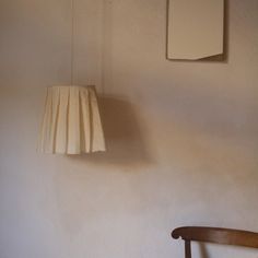 a lamp hanging from the side of a wall next to a wooden chair and table