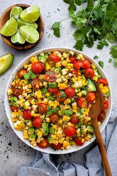 a bowl filled with corn, tomatoes and cilantro on top of a table