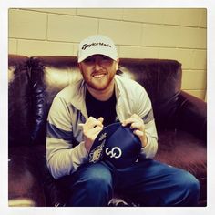 a man sitting on top of a brown leather couch holding a blue hat in his hands