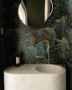 a white sink sitting under a bathroom mirror next to a wall mounted faucet