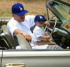 a man sitting in the driver's seat of a car with a little boy