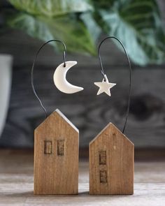 two small wooden houses with the moon and stars hanging from them, next to each other