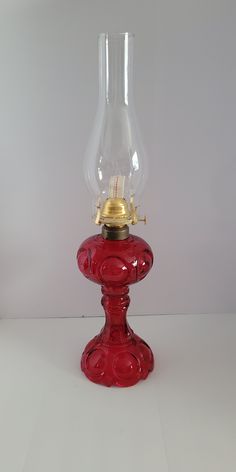 a red glass table lamp with a gold plated light bulb on it's base