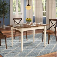 a dining room table with chairs and a rug on the floor in front of it