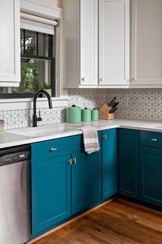 a kitchen with teal cabinets and white counter tops is pictured in this image, there are two dishes on the dishwasher