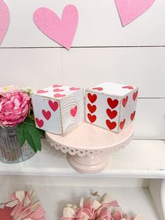 valentine's day decorations on a shelf with pink flowers and hearts hanging from the wall