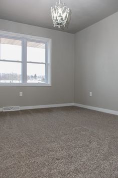 an empty room with a chandelier hanging from the ceiling and carpeted floor