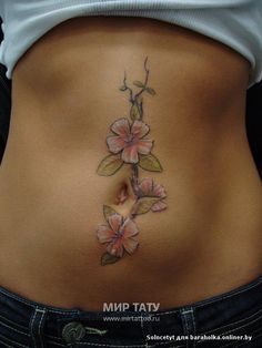 a woman's stomach with flowers tattooed on the side and behind her belly,