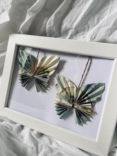 two origami butterflies are hanging in a white frame