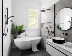 a white bath tub sitting under a bathroom mirror