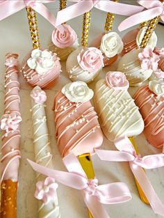 some pink and white decorated cookies on top of a table next to candy sticks with bows