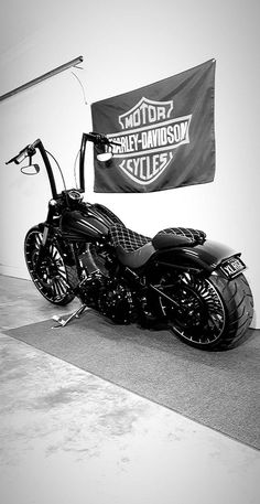 a black and white photo of a motorcycle parked in front of a harley davidson banner