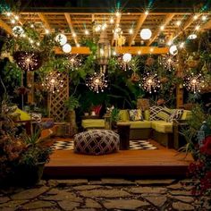 an outdoor living area with lots of plants and lights