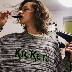 a man drinking from a wine glass while holding a hair dryer