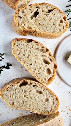 three pieces of bread sitting on top of a white plate next to butter and herbs