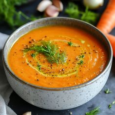 a bowl filled with carrot soup and garnished with herbs