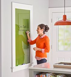 a woman writing on a green board in her kitchen