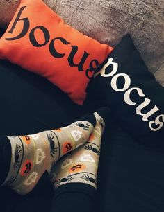 two pairs of socks sitting on top of a bed next to an orange pillow with the word booooies written on it