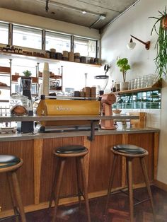 two bar stools sit in front of a counter with pots and plants on it