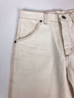 "1970's white denim Wrangler flares have contrast rust colored topstitching throughout, hip pockets, back patch pockets with curvy top stitching, and a zip fly with a metal stud button closure at the waist. Condition Excellent overall. Has some discolored spots on both front legs, and near the back hem. Theres a little bit of green discoloration on back metal rivets. Measurements Waist 26\" Hip 30\" Rise 10\" Inseam 31\" Length 40\"" White Straight Leg Jeans With Contrast Stitching, White Retro Pants With Pockets, Retro White Pants With Pockets, Retro White Bottoms With Pockets, White Retro Bottoms With Pockets, Vintage White Denim Jeans, Cream Cotton Flare Jeans, Retro White Straight Leg Jeans, Vintage White Bottoms With Pockets