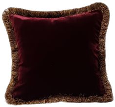 a dark red velvet pillow with brown fringe trimmings on the front and sides