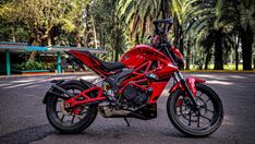 a red motorcycle parked in front of some trees