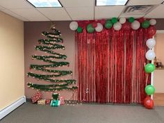 a decorated christmas tree in an office cubicle with balloons and streamers hanging from the ceiling