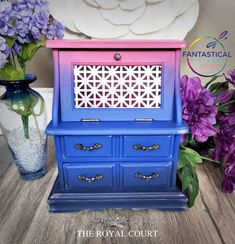 the royal court dresser is painted blue and pink with flowers in vases next to it