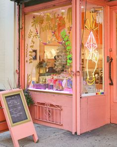 a pink store front with a sign in front of it