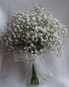 a bouquet of white baby's breath flowers on a white cloth covered tablecloth