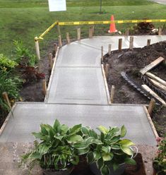 there is a cement walkway that has plants on it and yellow caution tape in the background