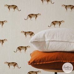 three pillows stacked on top of each other in front of a wallpaper with cheetah