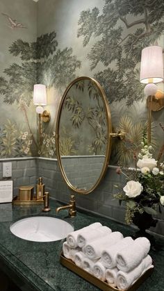 a bathroom with green marble counter tops and wallpapered walls, along with two gold faucets