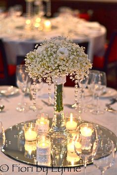 a centerpiece with flowers and candles on a table