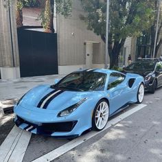 a blue sports car is parked on the side of the road next to another one