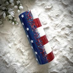 a red, white and blue can with stars on it sitting next to some flowers