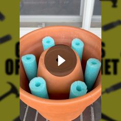 a clay pot filled with lots of blue and brown items in front of a window