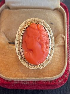 This vintage ring features a stunning orange coral stone set in a beautiful 14k yellow gold setting. The intricate details of the Cameo are visible in the design of this antique piece. The ring is a unique addition to any collection and perfect for those who appreciate vintage and antique jewelry. The coral stone is a beautiful material that adds a touch of elegance to any outfit. This ring is a must-have for any jewelry lover. Box not included. Size 9. 14k Gold Cameo Ring Fine Jewelry, Vintage Coral Jewelry For Anniversary, Coral Vintage Jewelry For Anniversary, Vintage Oval Coral Jewelry, Vintage Coral Rings As A Gift, Vintage Coral Oval Jewelry, Antique Orange Jewelry For Wedding, Antique Orange Oval Ring, Vintage Coral Jewelry For Wedding